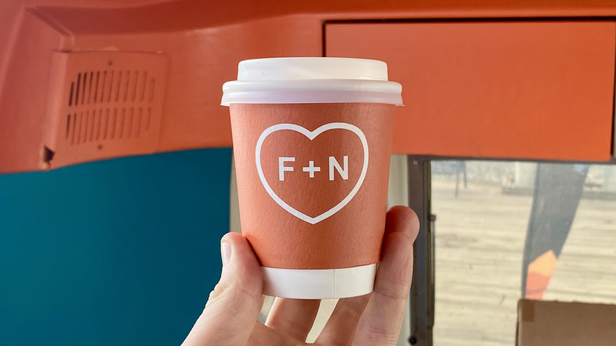 F + N heart mark printed on a coral takeaway cup.