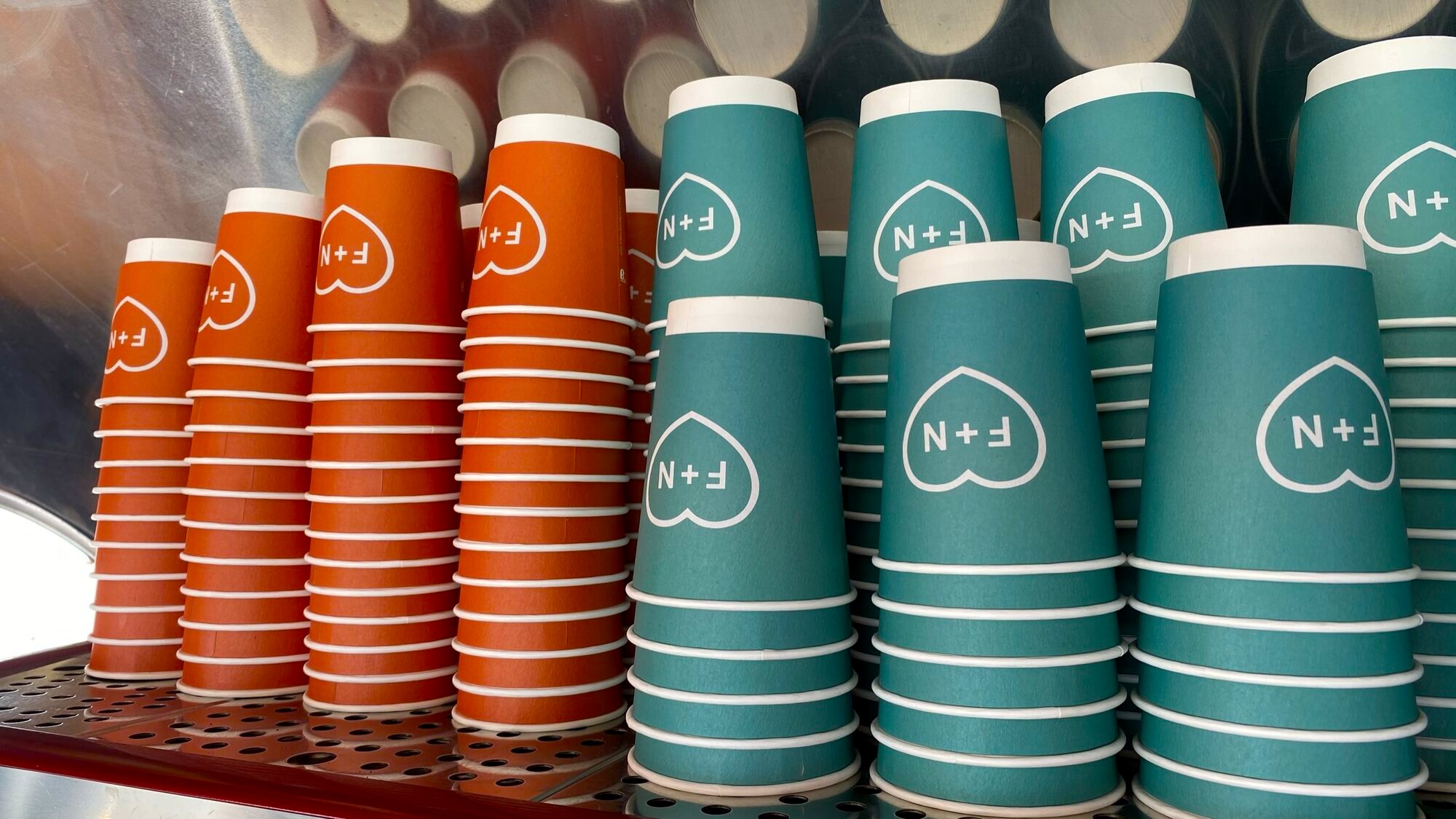 Stacks of Fred + Nancy’s coral and teal F+N-heart cups inside the Airstream.