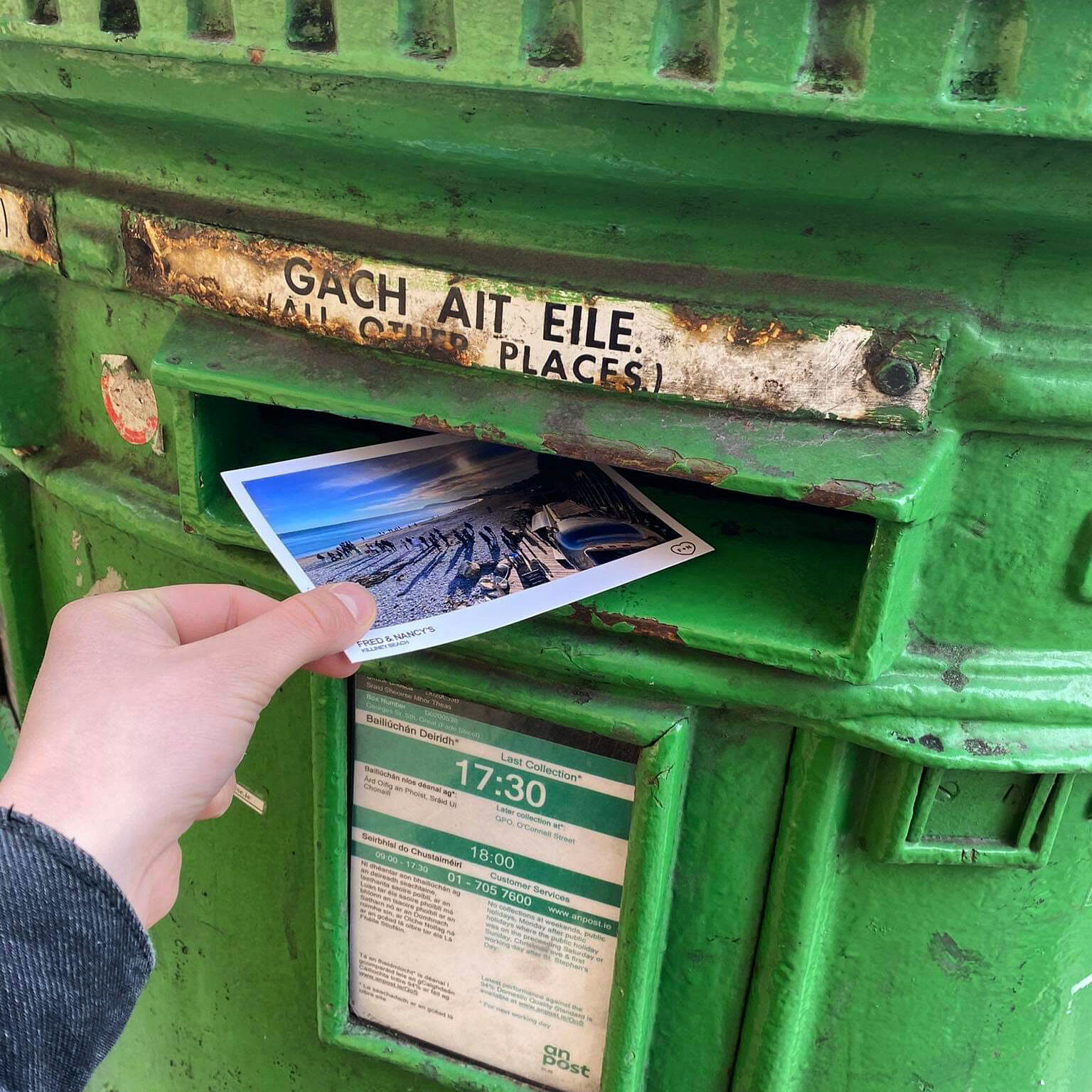 A Fred + Nancy's postcard being posted into a beach postbox.