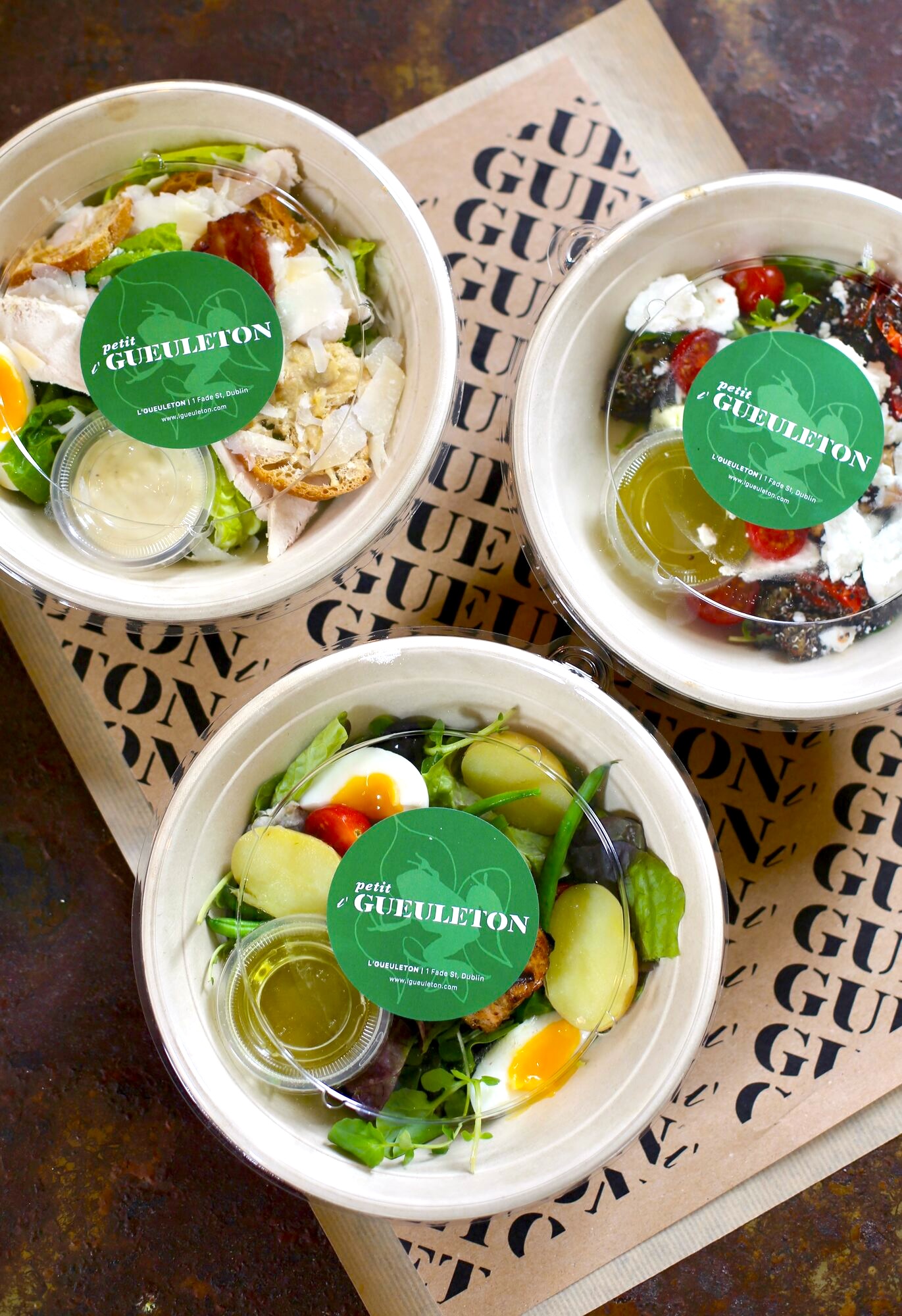 Petit L'Gueuleton takeaway salad bowls with green stickers.