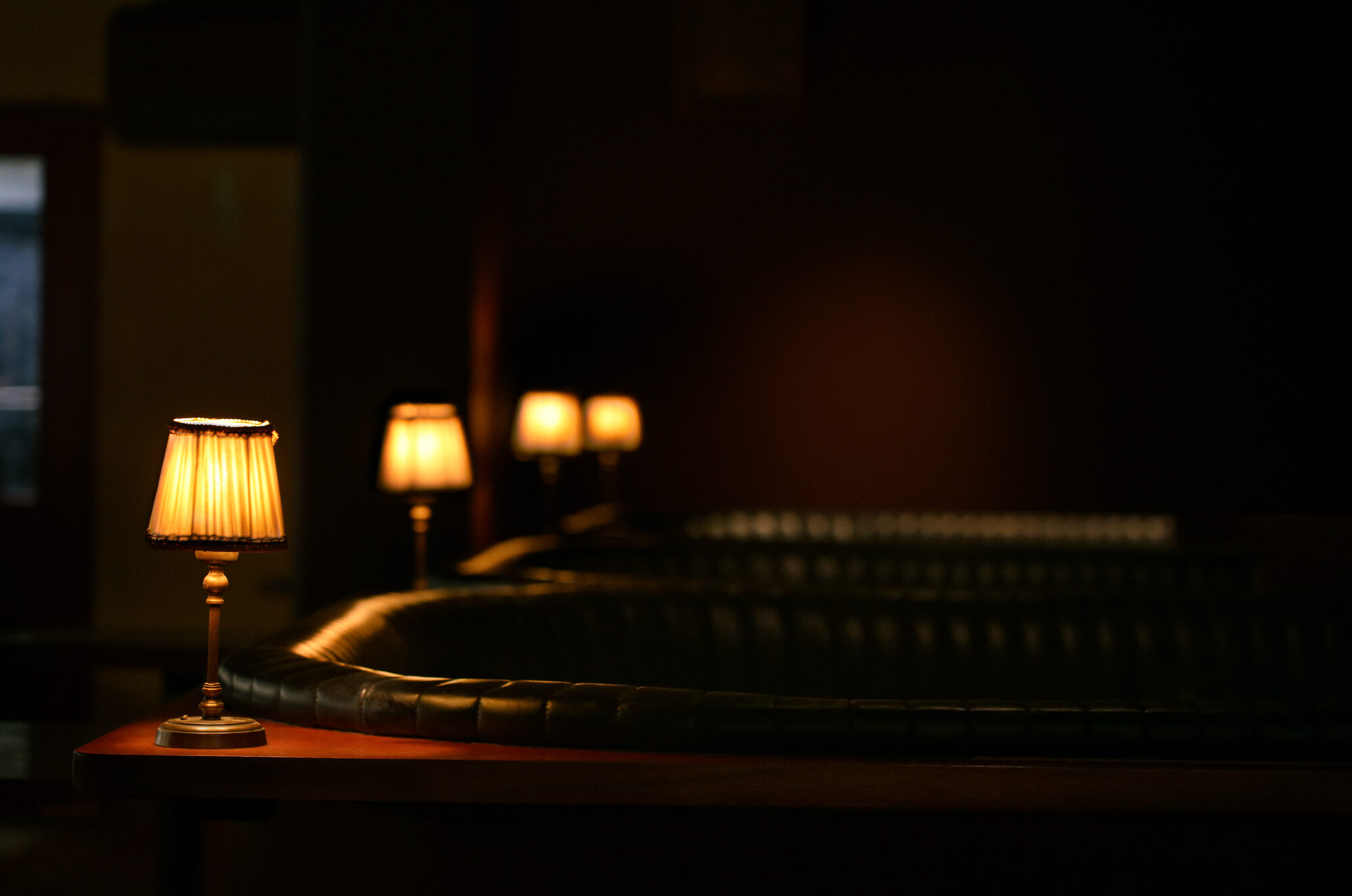 Low-lit Luna dining room with booths, table lamps and an open kitchen in the background.