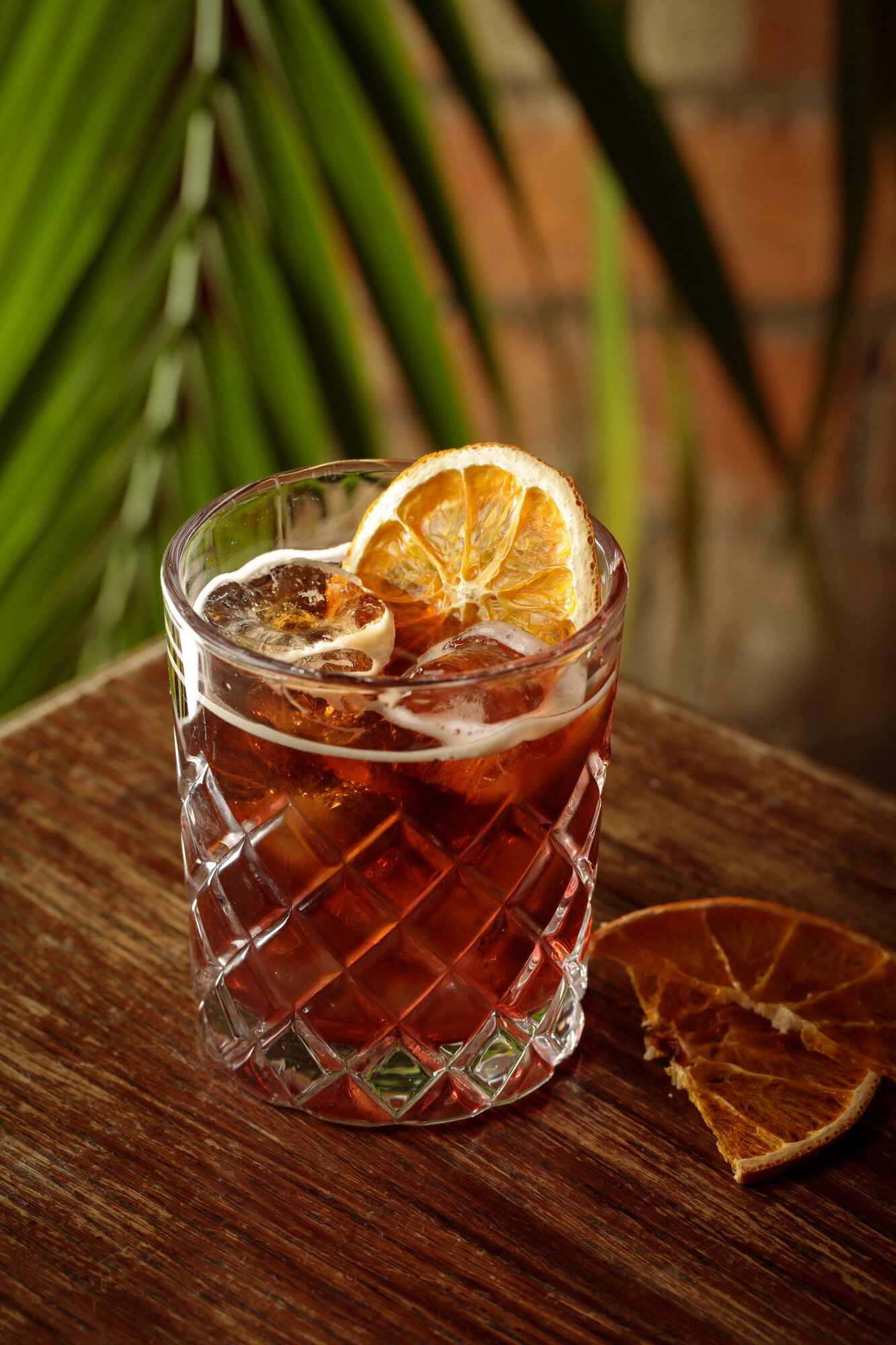 Warm orange cocktail with leaf garnish.