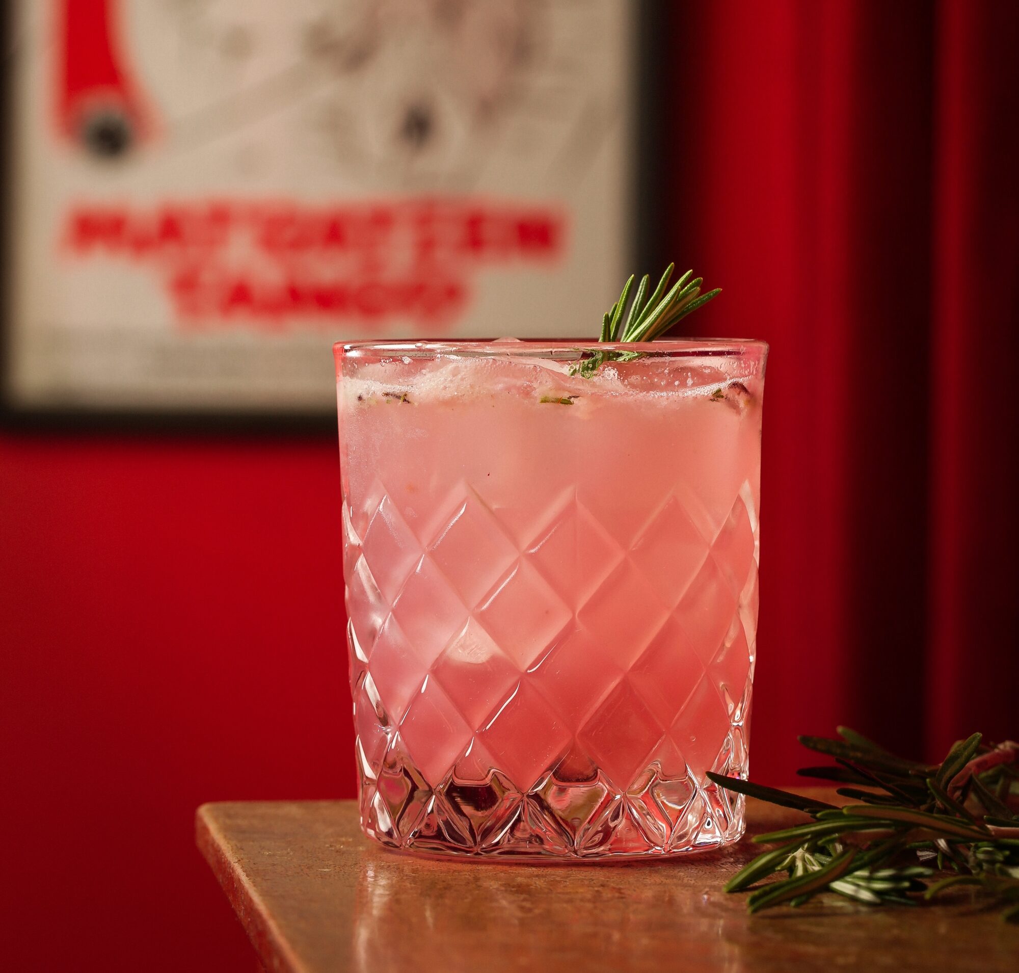 Pink cocktail against a deep red curtain.